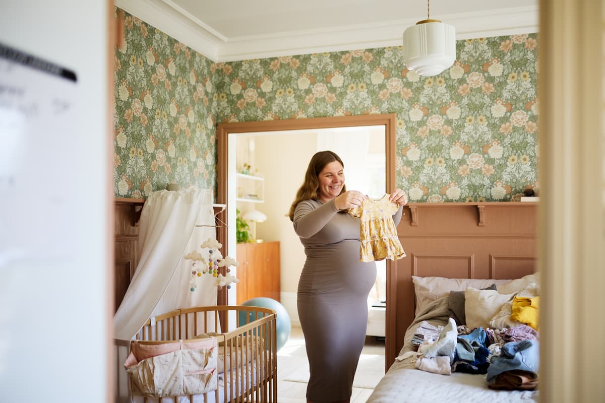 hvordan velge sprinkelseng: en kvinne forbereder et rom for en baby