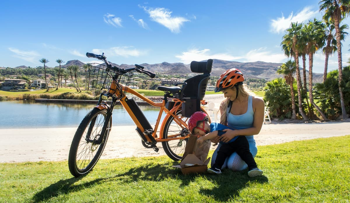 elsykkel med barnesete kvinne med et barn: på gresset ved en elektrisk sykkel