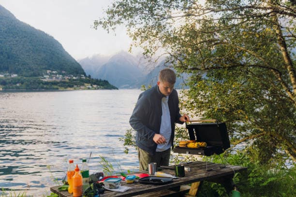 liten gassgrill: en mann griller i naturen