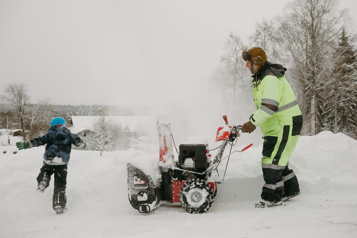 hvordan velge riktig snøfreser: en mann med et barn rydder snø
