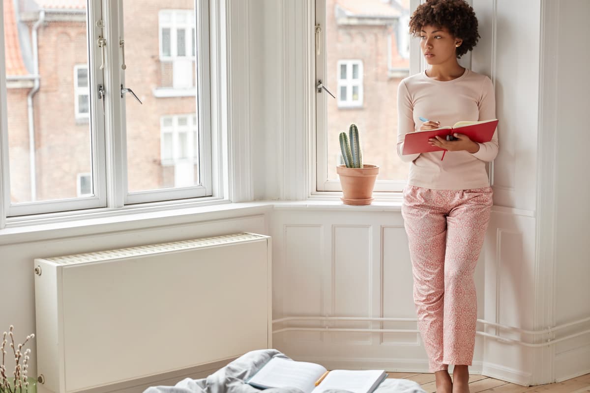 hvordan velge panelovn: kvinne ved radiatoren